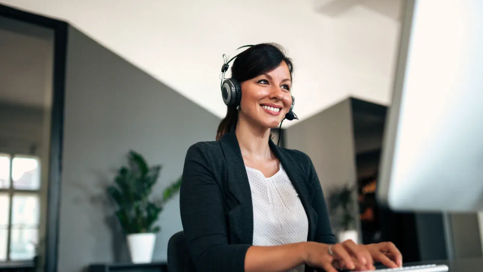 Atendente sorridente com fone de ouvido, trabalhando no computador